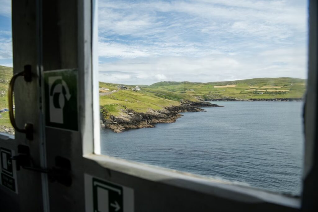 Vue d'une fenetre de train sur la mer et la côte recouverte de verdure