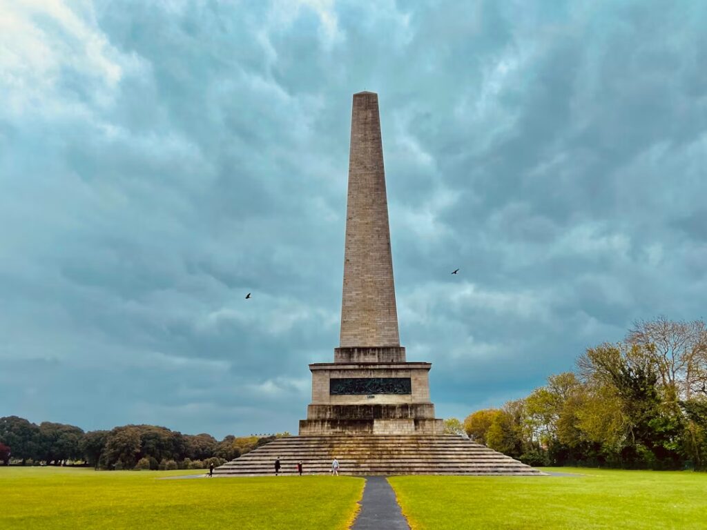 Monument légérement conique installé sur du gazon et entouré d'arbres