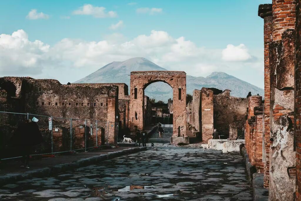 Ruines de batiments en pierres avec rues pavées et volcan en arriere plan