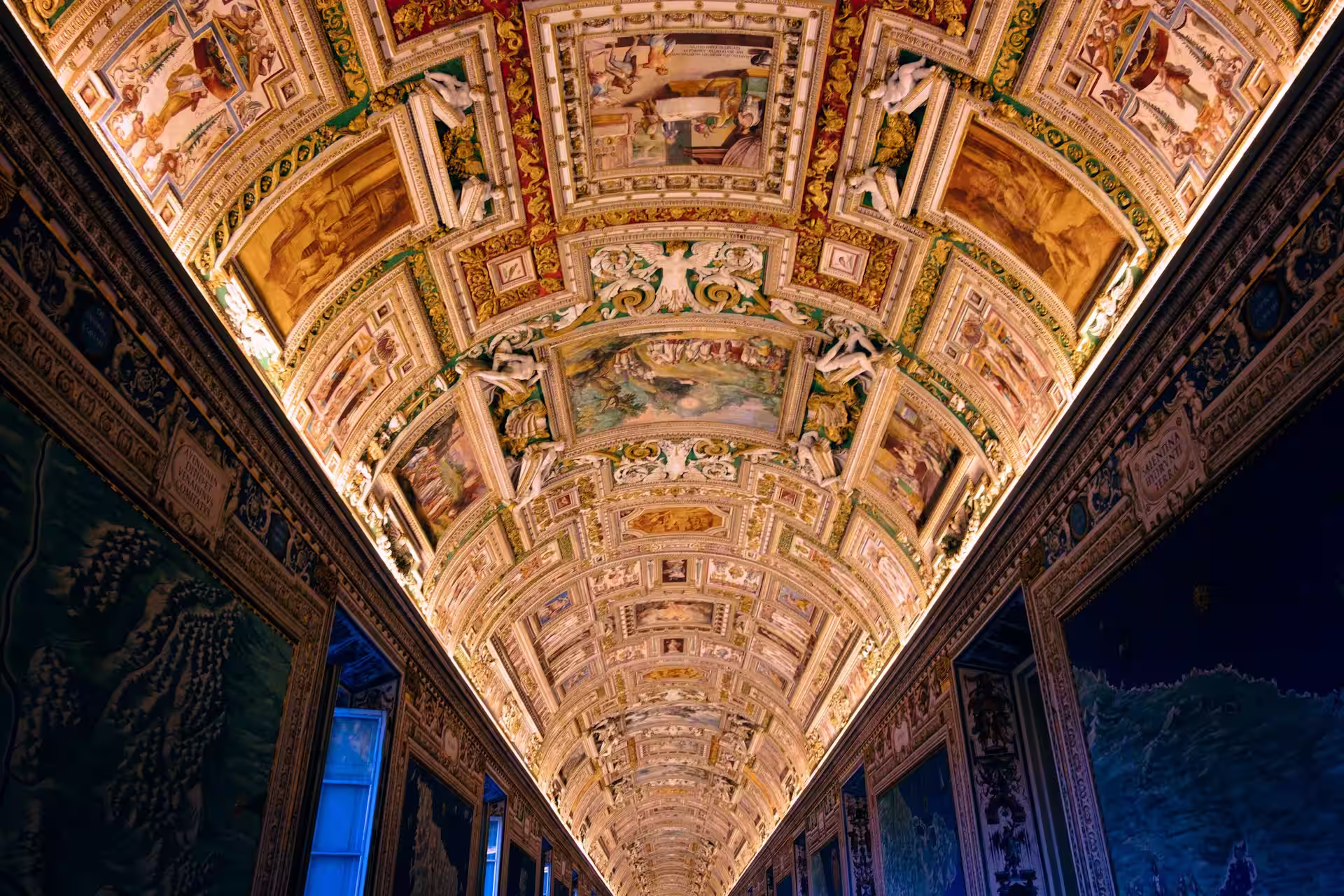 Plafond orné de peintires eclairées dans une salle longue