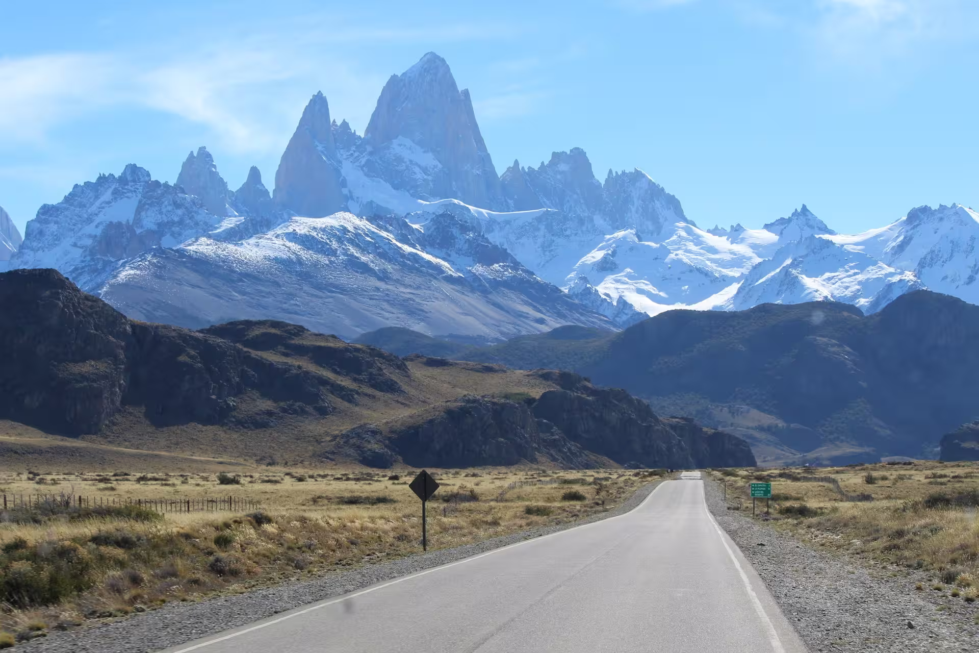 route traversant le paysage vers des montagnes aux pics acérés enneigés