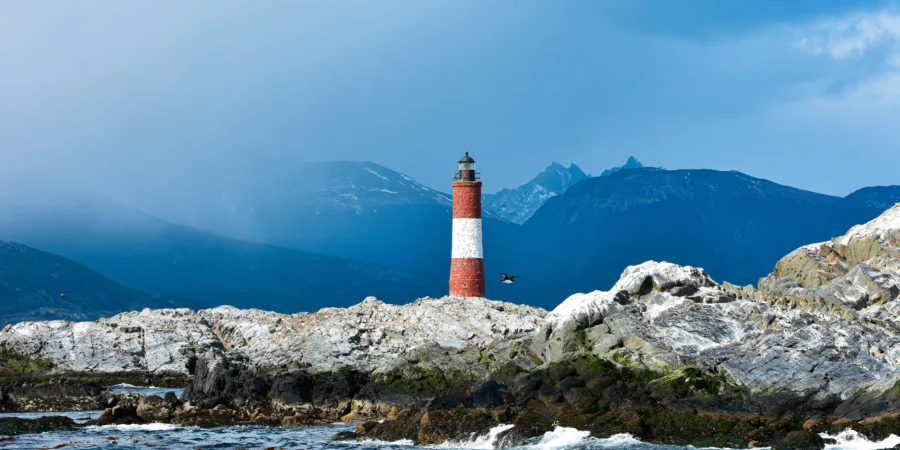 un phare rouge et blanc assis au sommet dun rivage rocheux